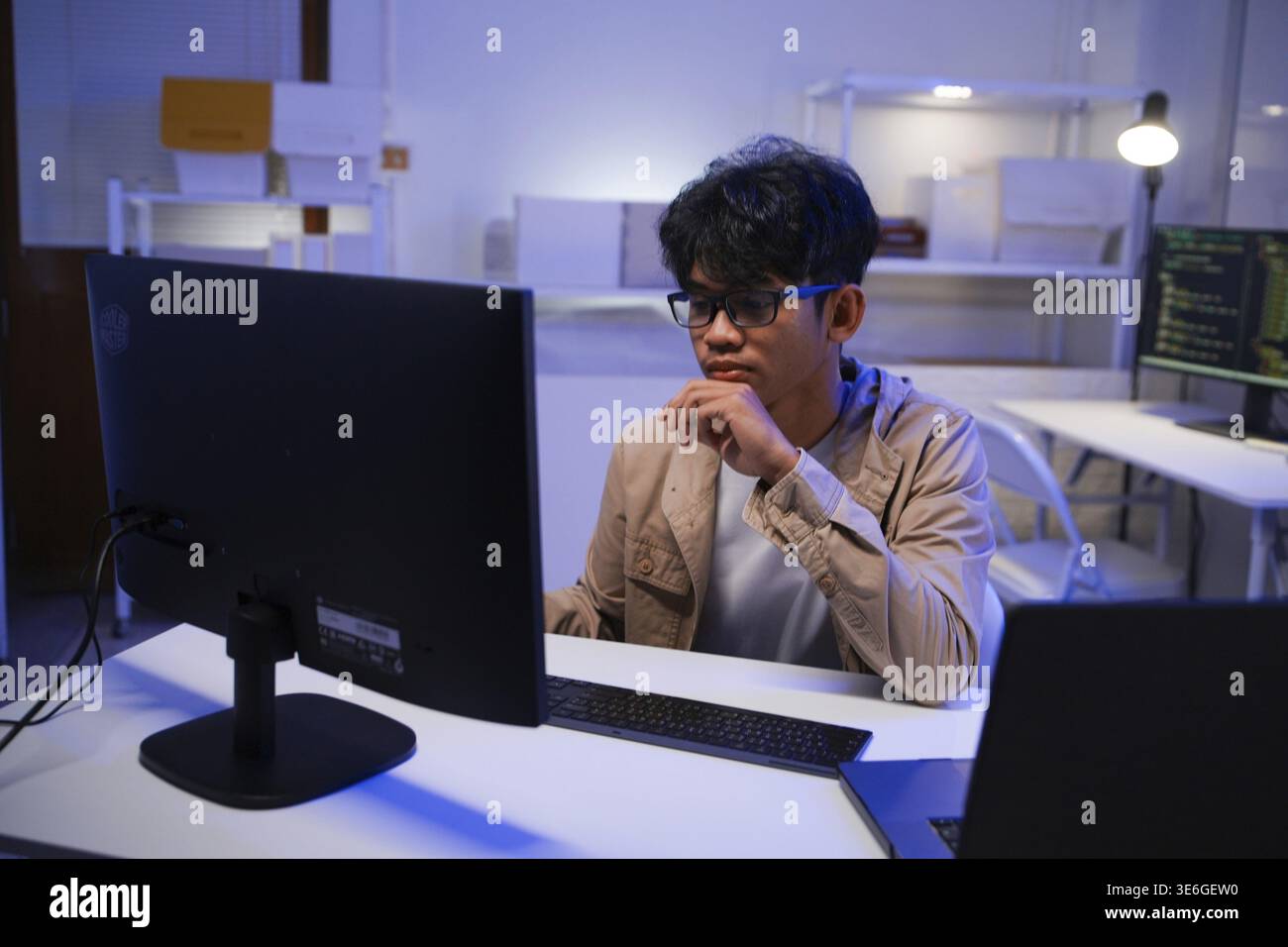 Male Software Engineer Writing Code on Desktop Computer with Multiple Screens Setup. Data center programmer managing large datasets used in AI trainin Stock Photo