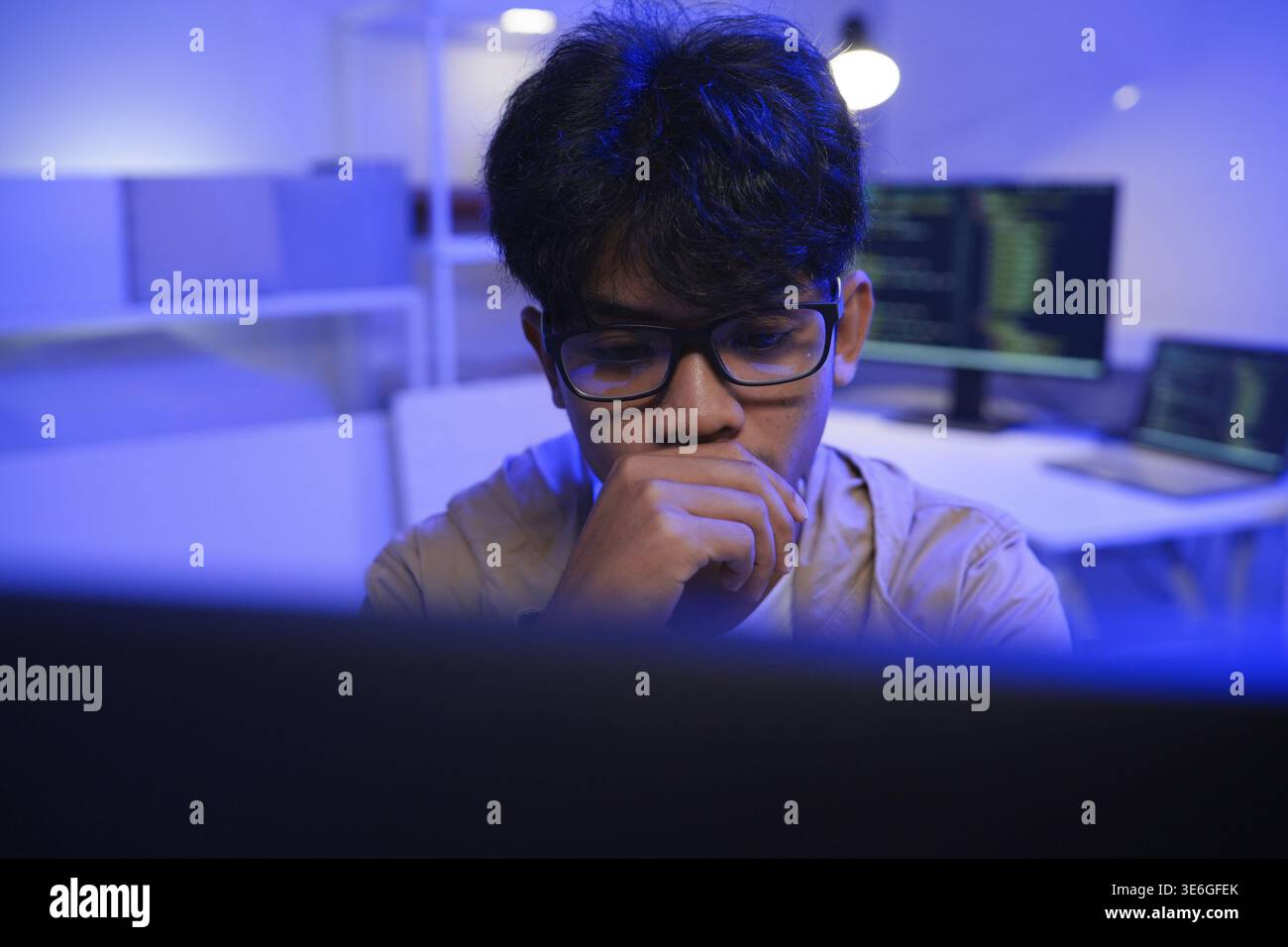 Male Software Engineer Writing Code on Desktop Computer with Multiple Screens Setup. Data center programmer managing large datasets used in AI trainin Stock Photo