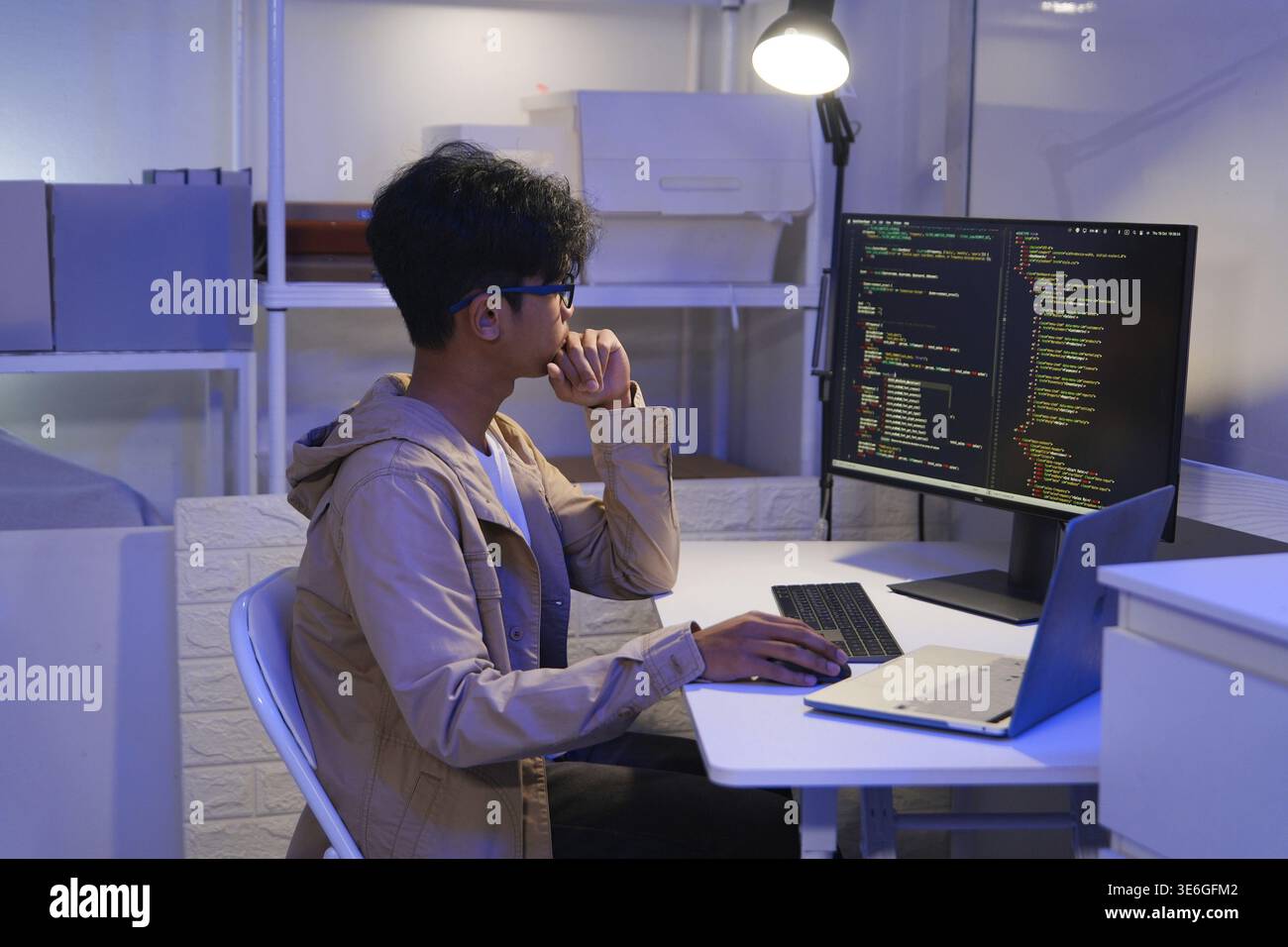 Male Software Engineer Writing Code on Desktop Computer with Multiple Screens Setup. Data center programmer managing large datasets used in AI trainin Stock Photo