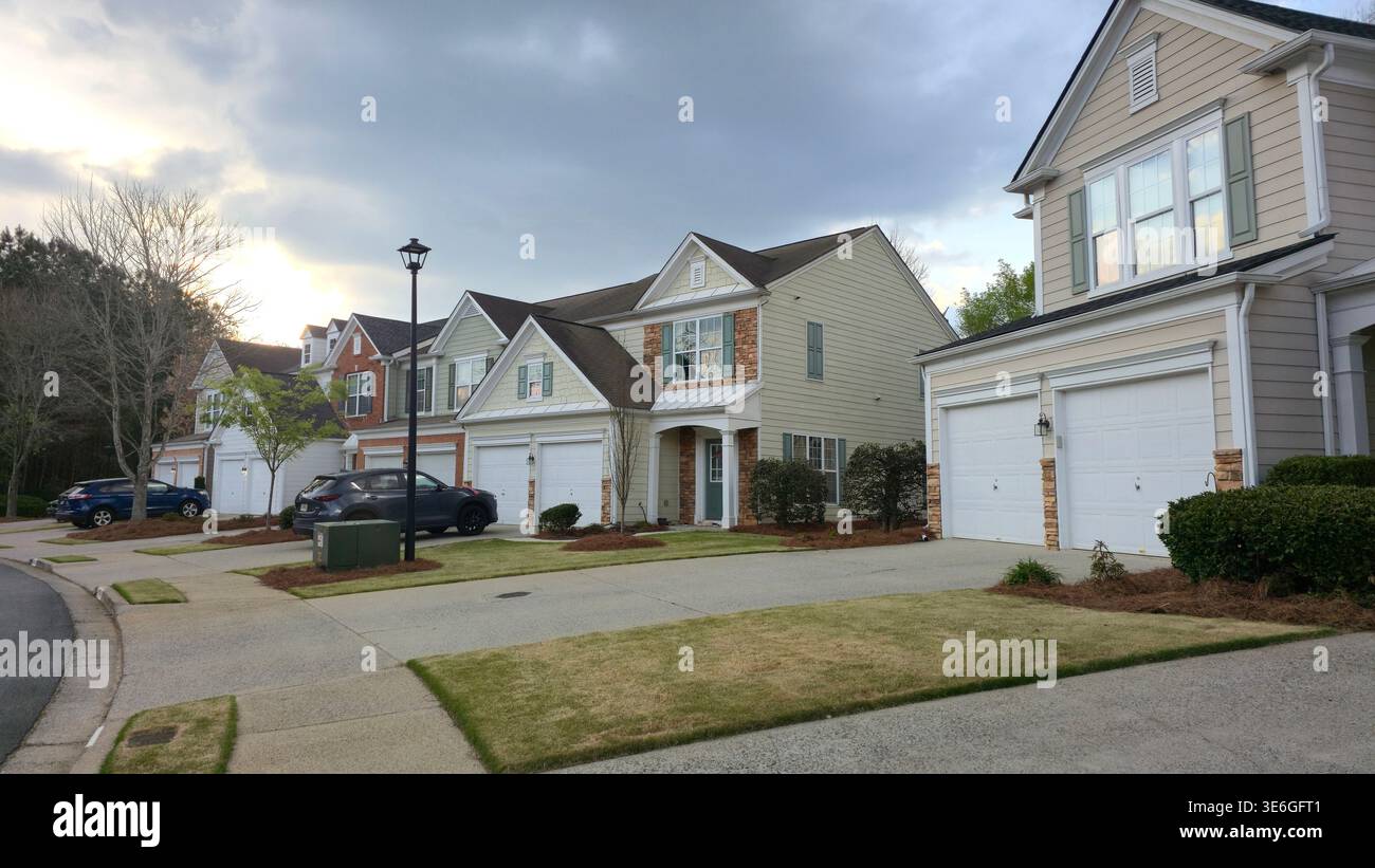 Row of suburban houses with garages and parked cars on quiet residential street at sunset, typical American neighborhood - Smartphone Captured Stock Image