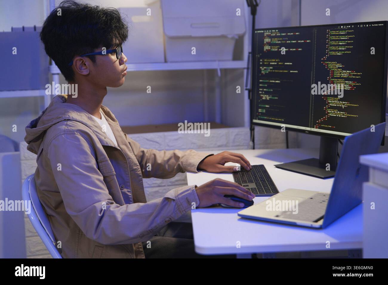 Male Software Engineer Writing Code on Desktop Computer with Multiple Screens Setup. Data center programmer managing large datasets used in AI trainin Stock Photo