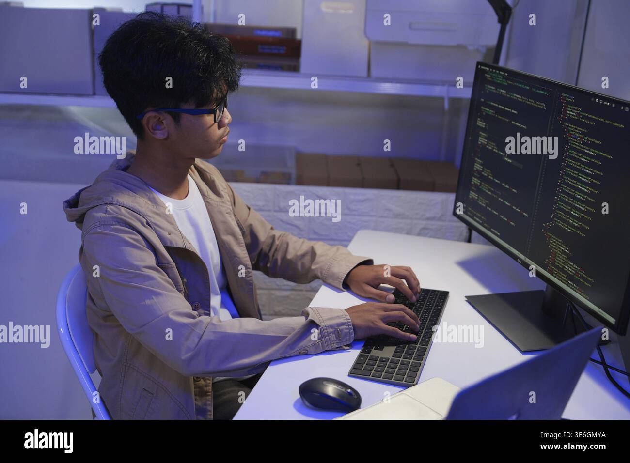 Male Software Engineer Writing Code on Desktop Computer with Multiple Screens Setup. Data center programmer managing large datasets used in AI trainin Stock Photo