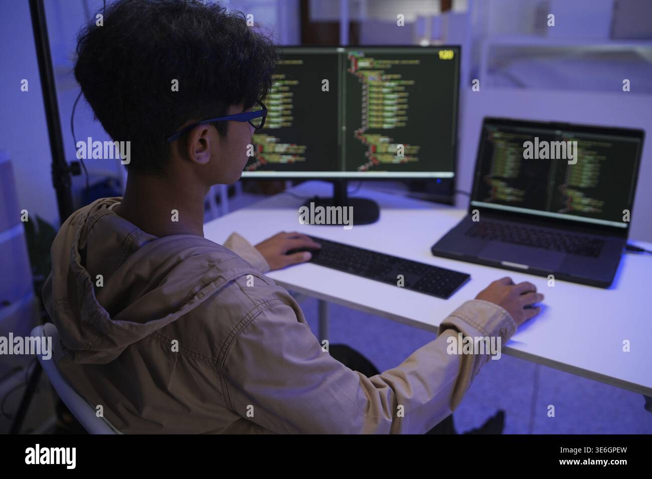 Male Software Engineer Writing Code on Desktop Computer with Multiple Screens Setup. Data center programmer managing large datasets used in AI trainin Stock Photo