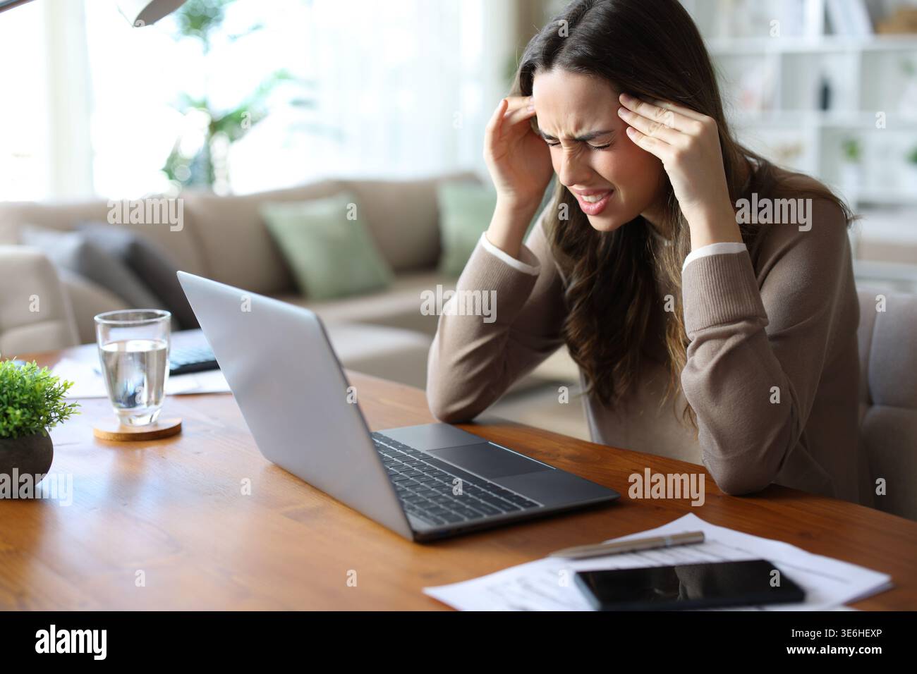 Stressed tele worker suffering migraine attack and complaining while working at home Stock Photo