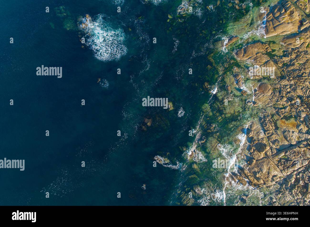 Top down aerial photography of deep blue ocean water meeting rugged ...