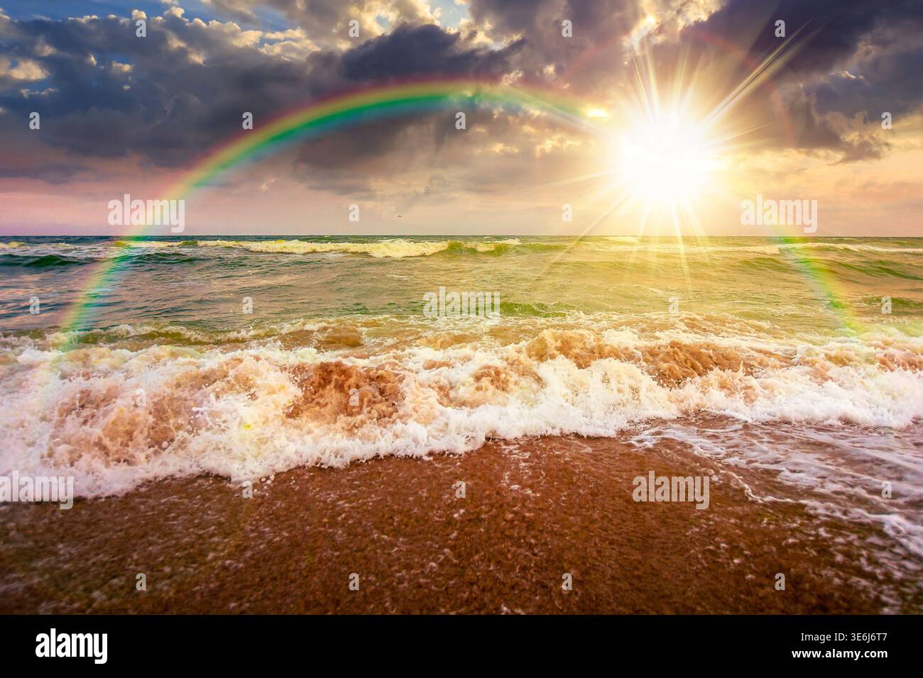 stormy weather on the sandy beach at sunset. dramatic sky over the sea in evening light. moody summer landscape. green waves crashing the shore. majes Stock Photo