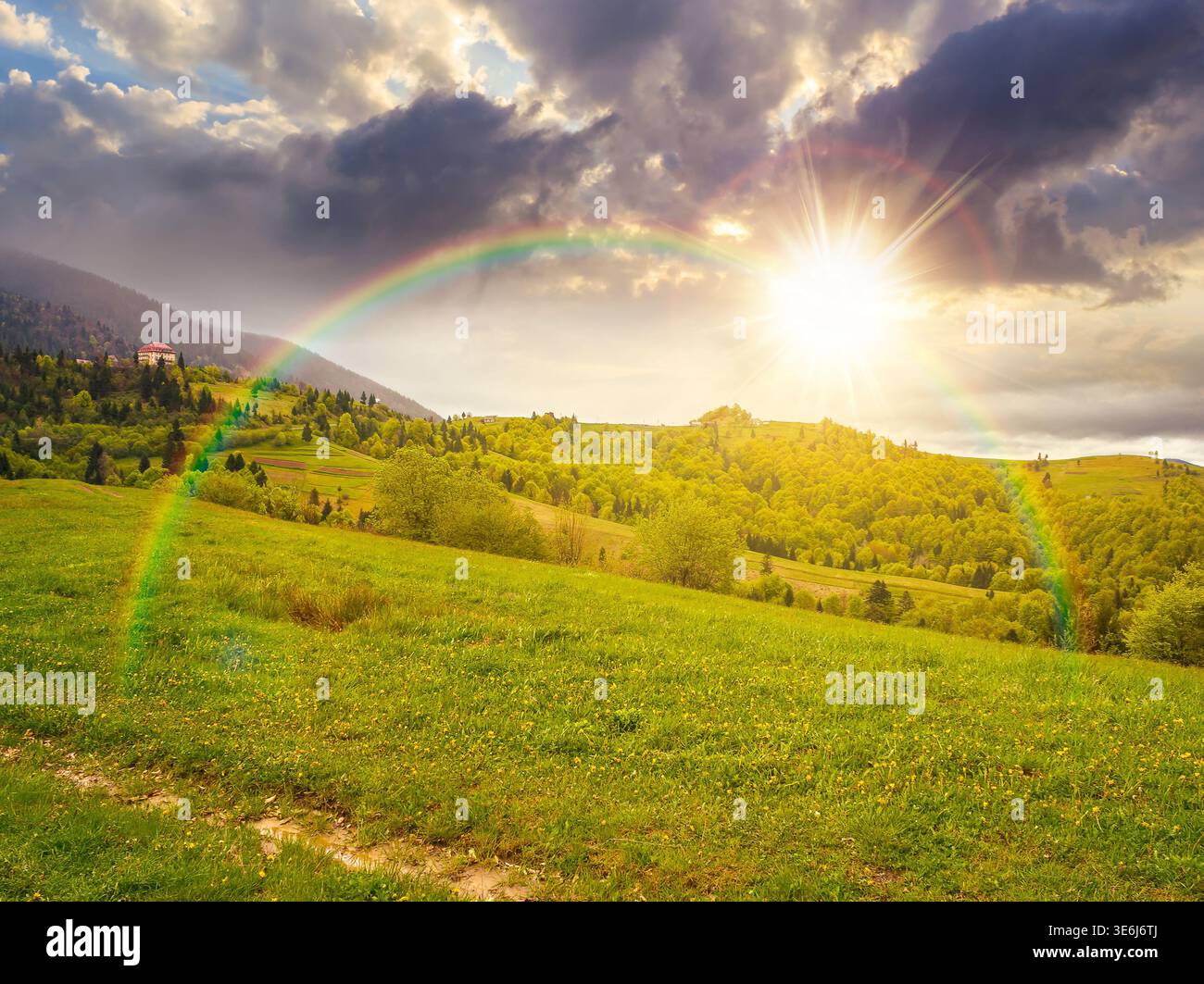 remote countryside in mountain landscape at sunset. hazy weather during spring in evening light. dirt road through lush green pasture on a hill. alpin Stock Photo