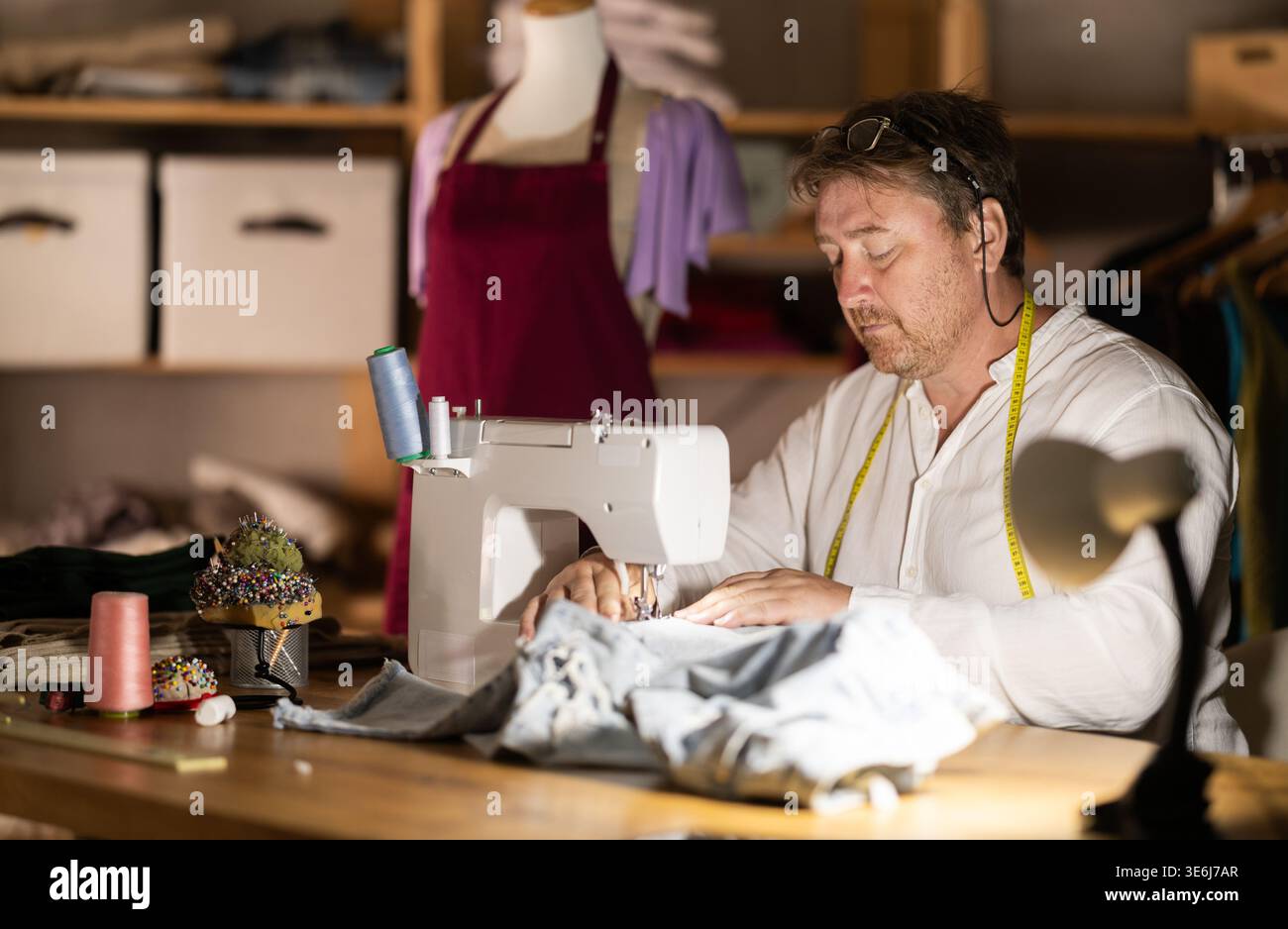 Middle-aged male dressmaker working with sewing-machine Stock Photo
