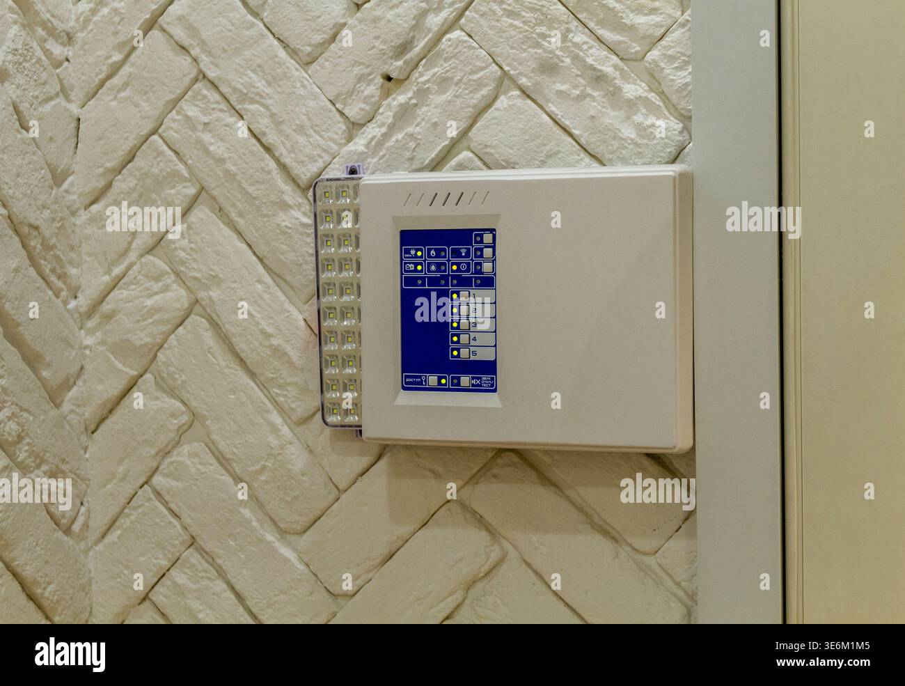 The image shows a security control panel mounted on a textured white wall. Stock Photo