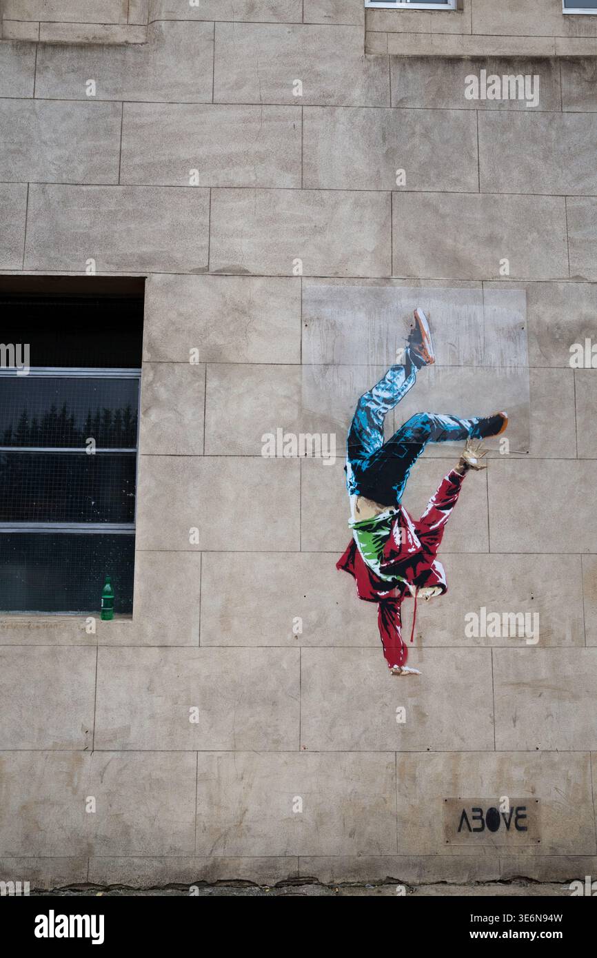 A colourful paste-up mural by street artist Above shows a breakdancer frozen in a dynamic handstand on a stone building facade in London Stock Photo