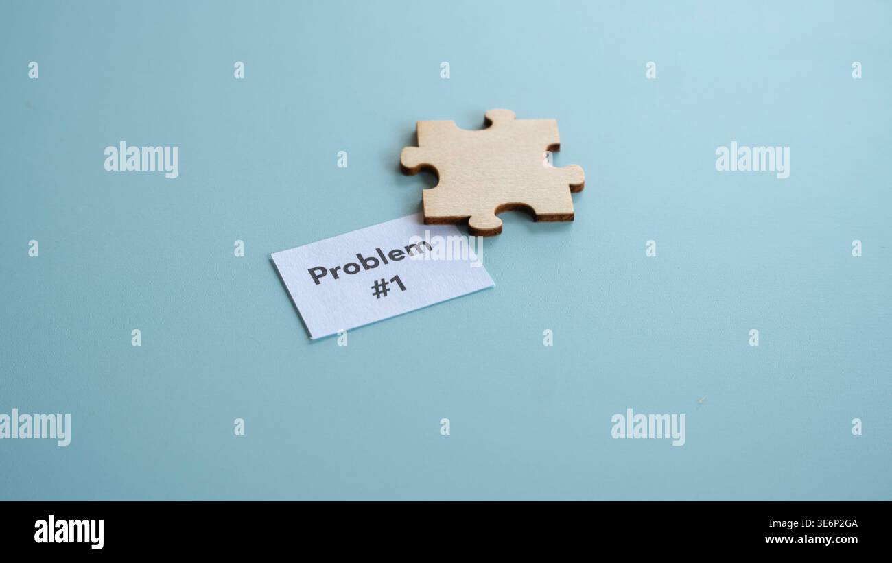 Single wooden puzzle piece next to paper labeled problem number one Stock Photo