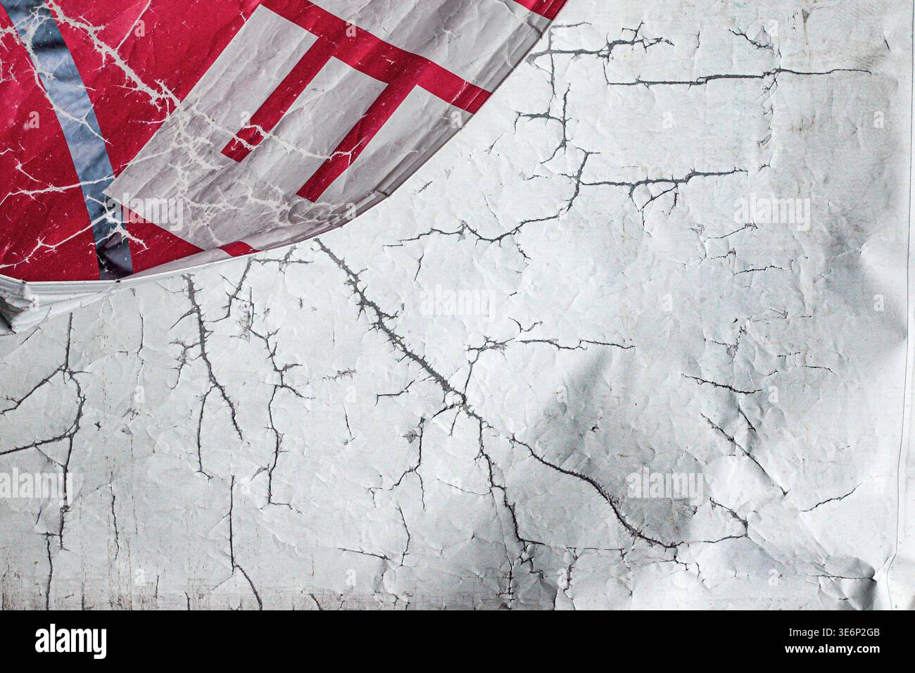 Cracks spread like a web on a white textured surface with deep, dark shadows. Stock Photo