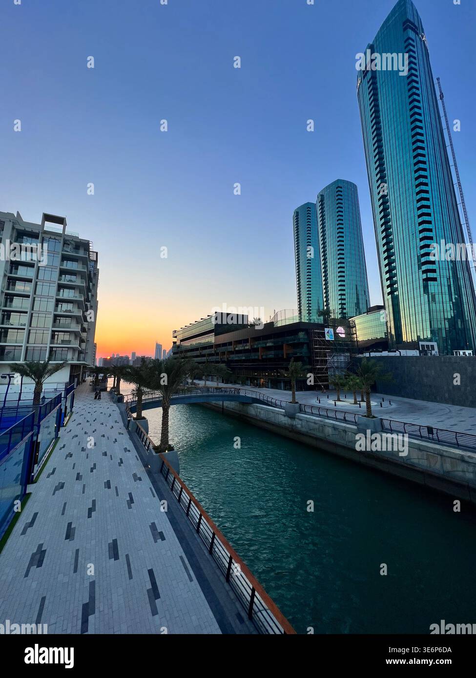 Waterfront promenade and canal at Bahrain Bay in Manama, Bahrain, with modern residential and office towers at dusk. - Smartphone Captured Stock Image