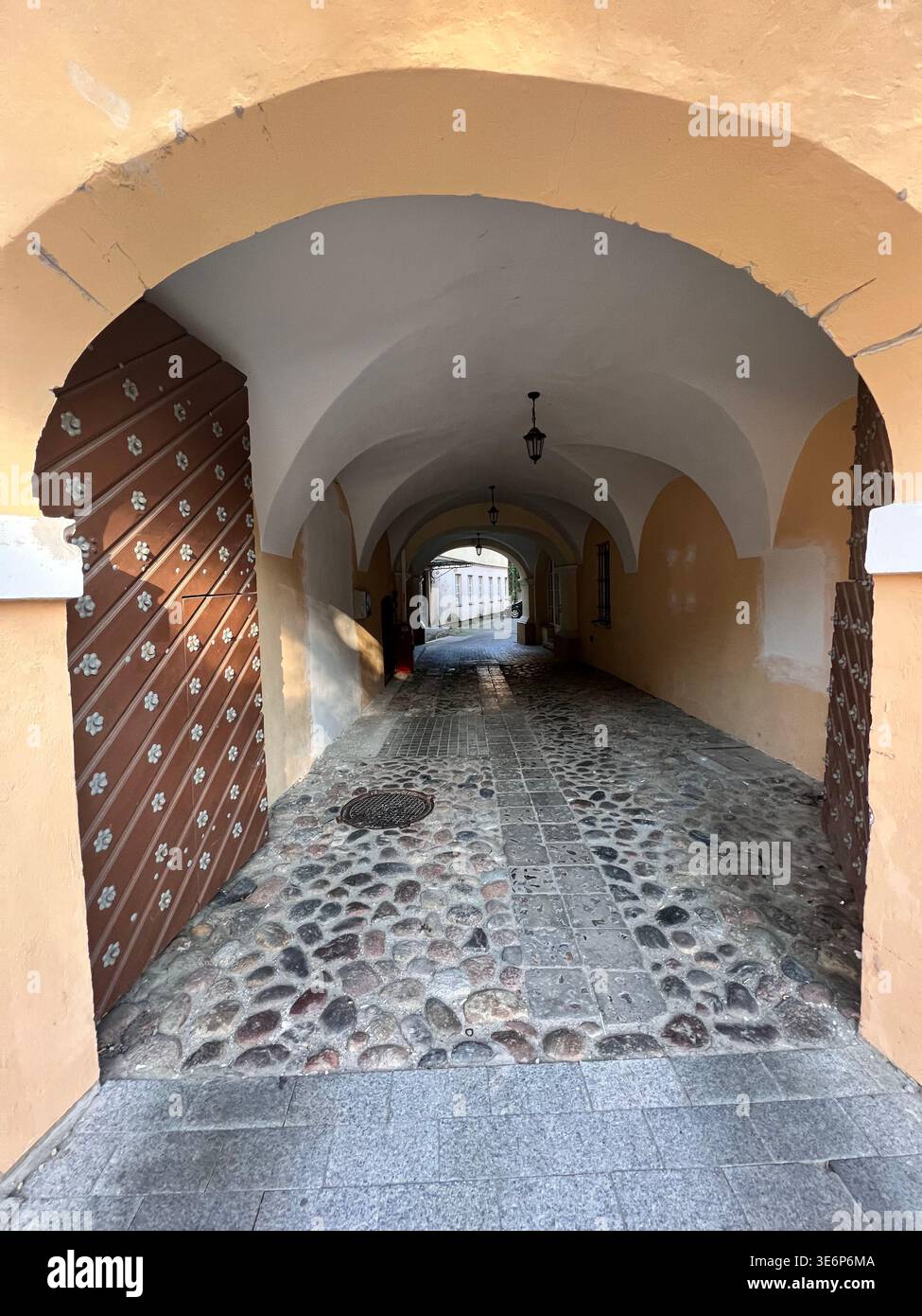 Arched passageway with stone paving in Vilnius Old Town, Vilnius, Lithuania. - Smartphone Captured Stock Image