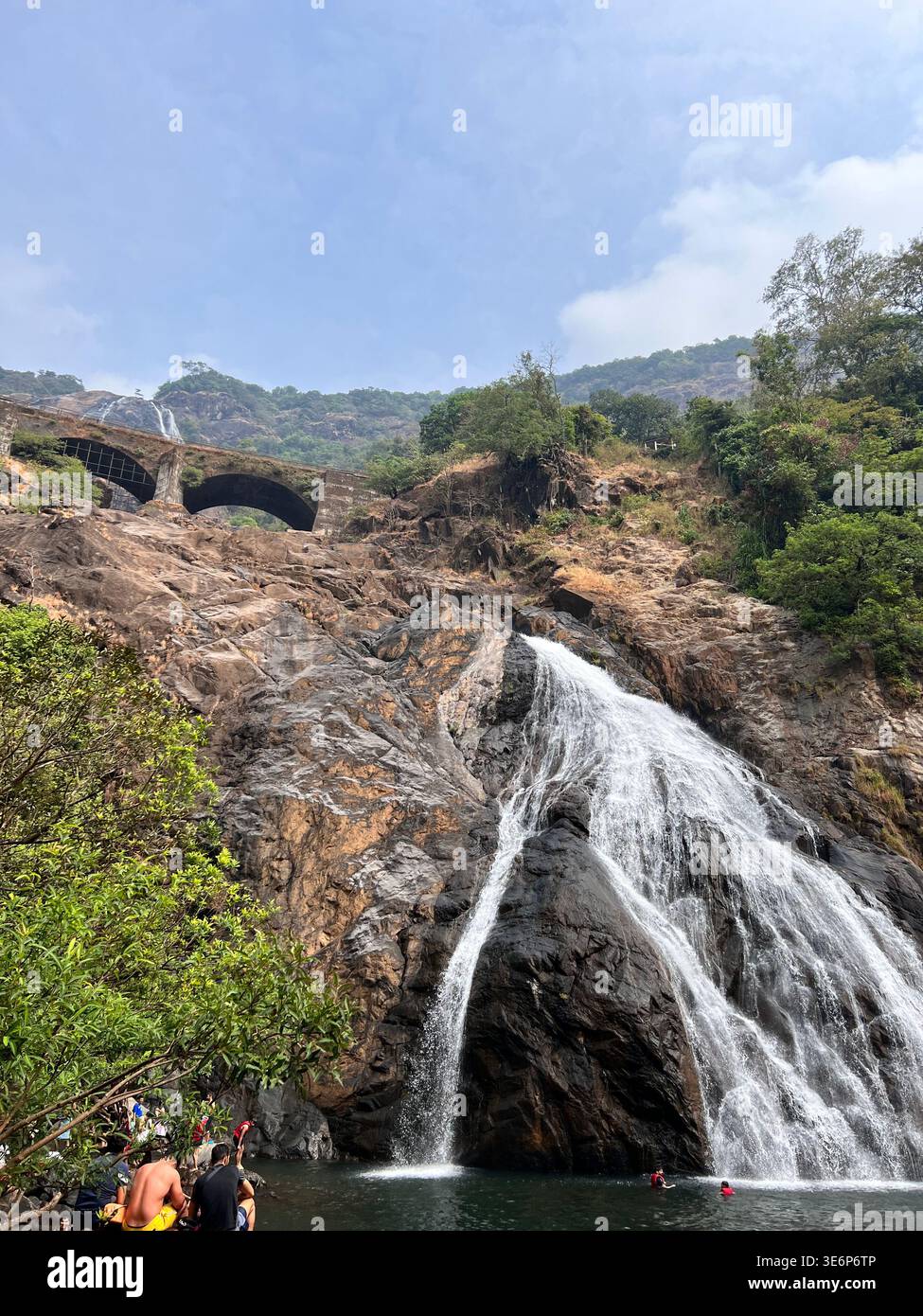 Lower cascade of Dudhsagar Falls with railway bridge and visitors in Goa, India. - Smartphone Captured Stock Image