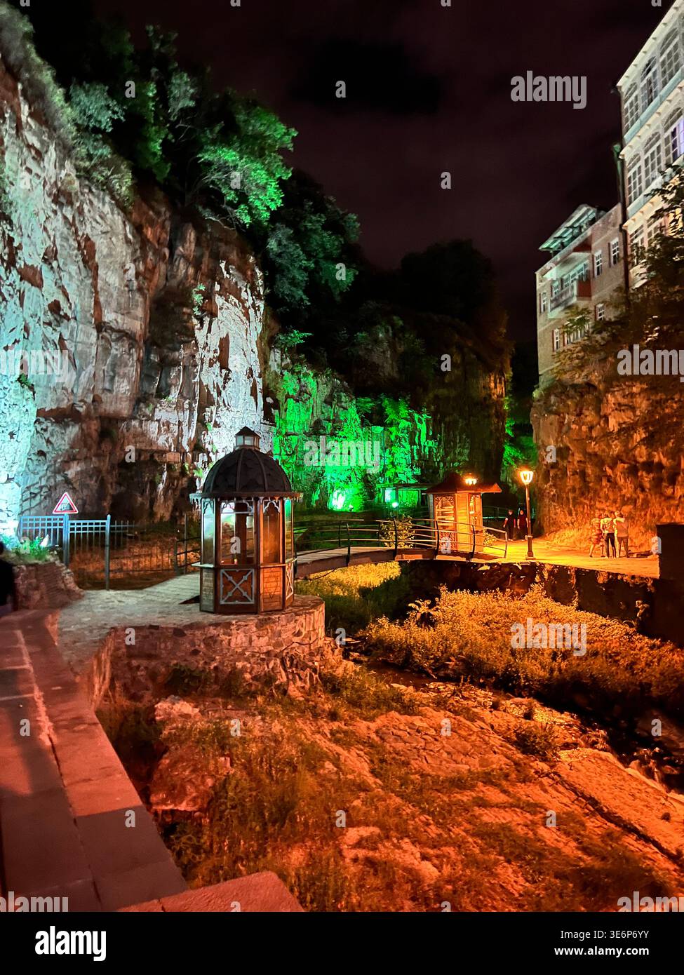 Illuminated rocky gorge and pedestrian walkway at night in the Abanotubani district of Tbilisi, Georgia. - Smartphone Captured Stock Image