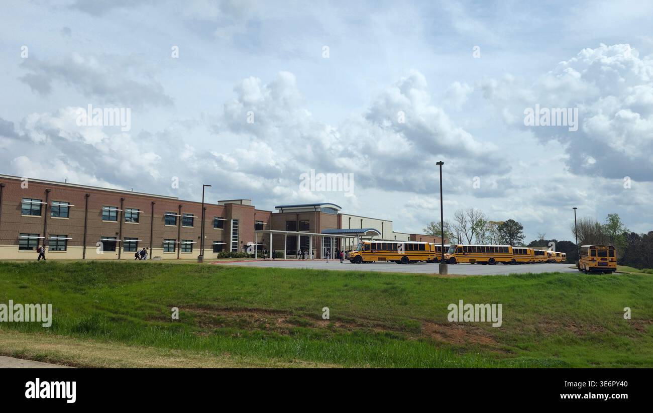 School building with yellow school buses and students near entrance, typical American public school campus, USA - Smartphone Captured Stock Image