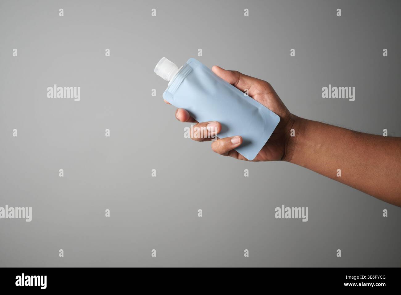 Holding a blue bottle in hand in a plain background Stock Photo - Alamy