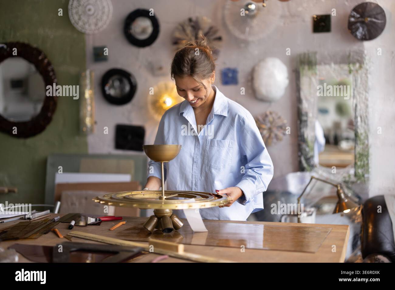 Artisan collecting parts of handcrafted sconce lamp in workshop Stock Photo