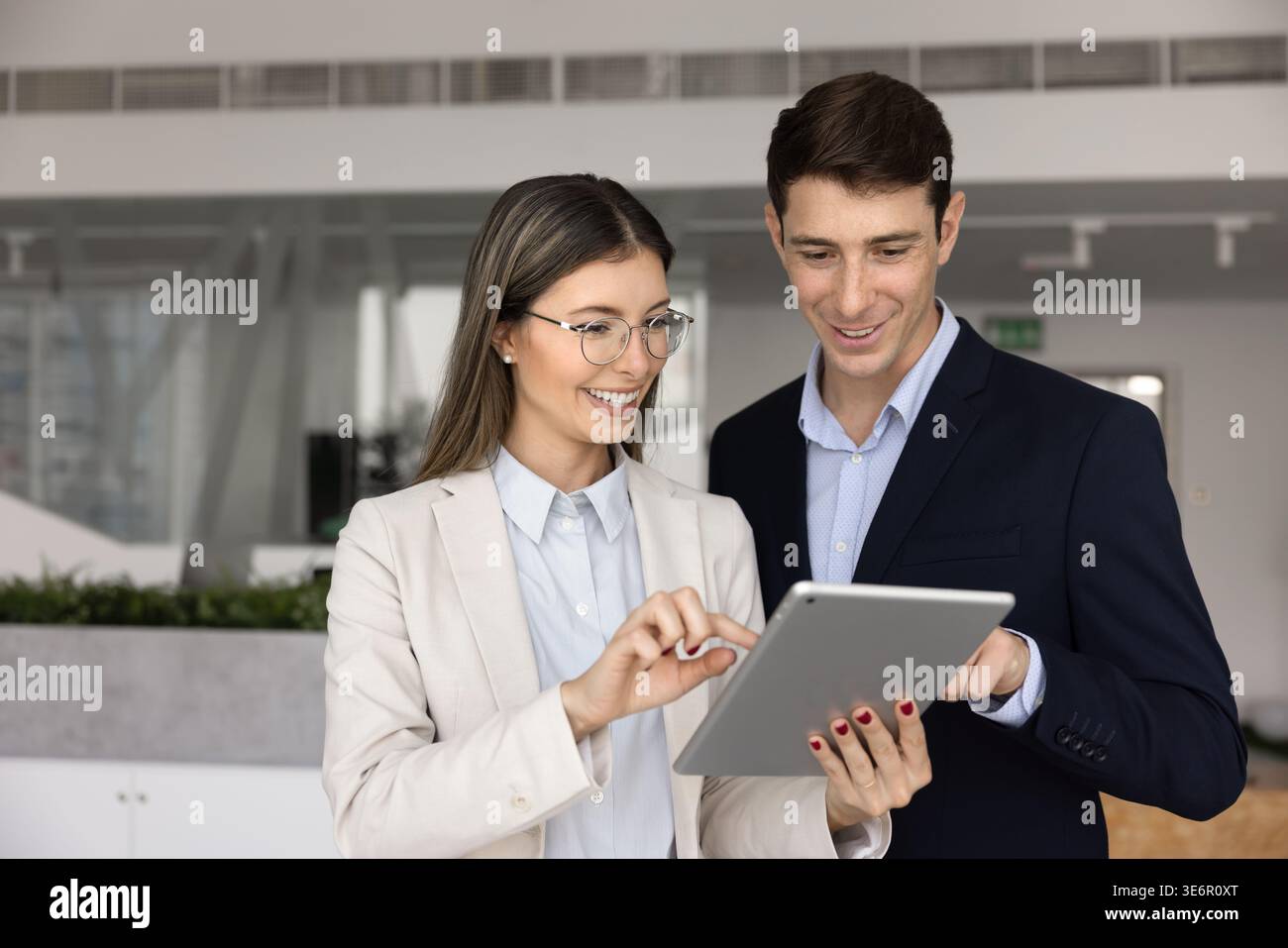 Two smiling colleagues working on task using tablet Stock Photo