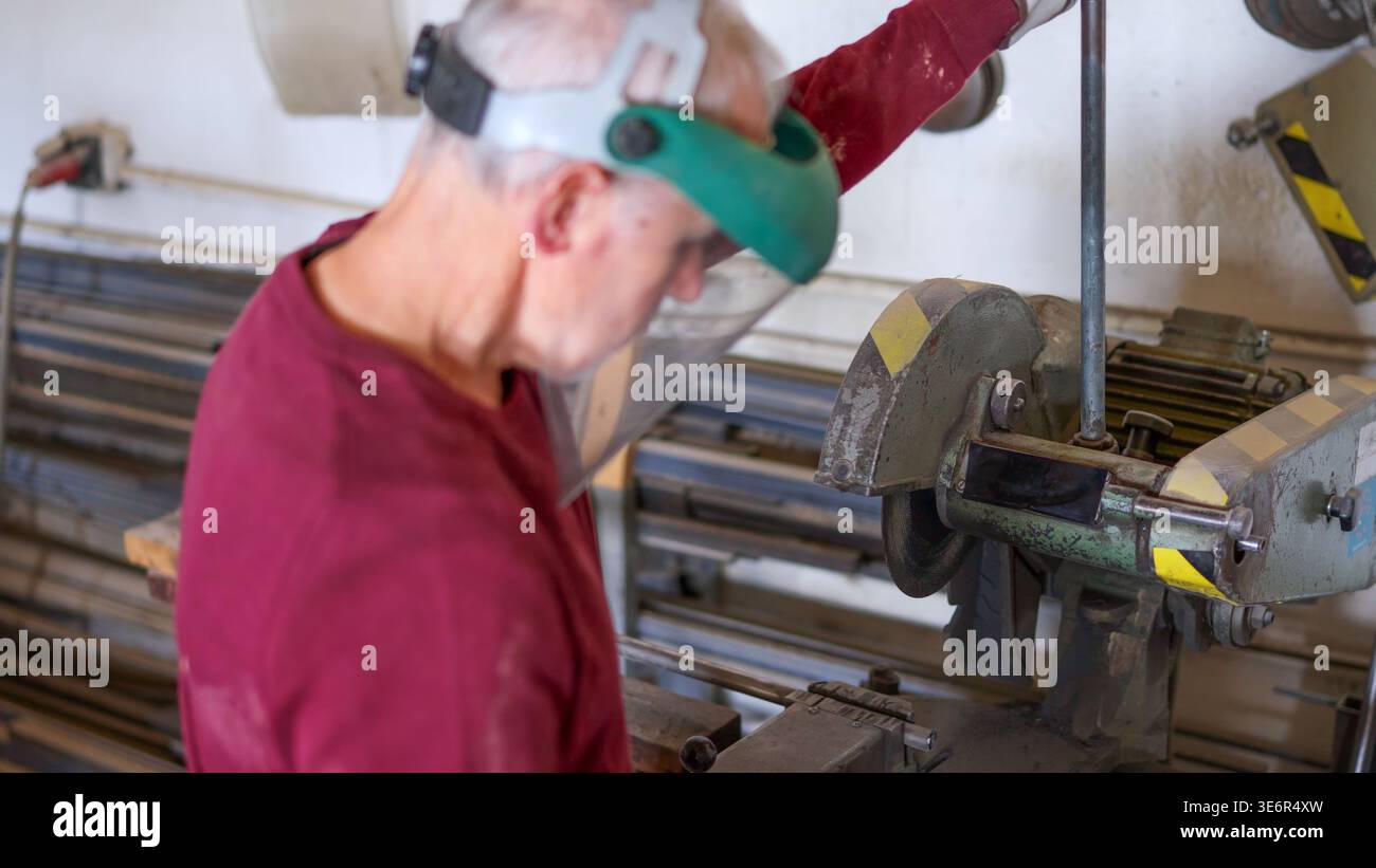 Worker shaping metal profile using cutting machine in workshop Stock Photo