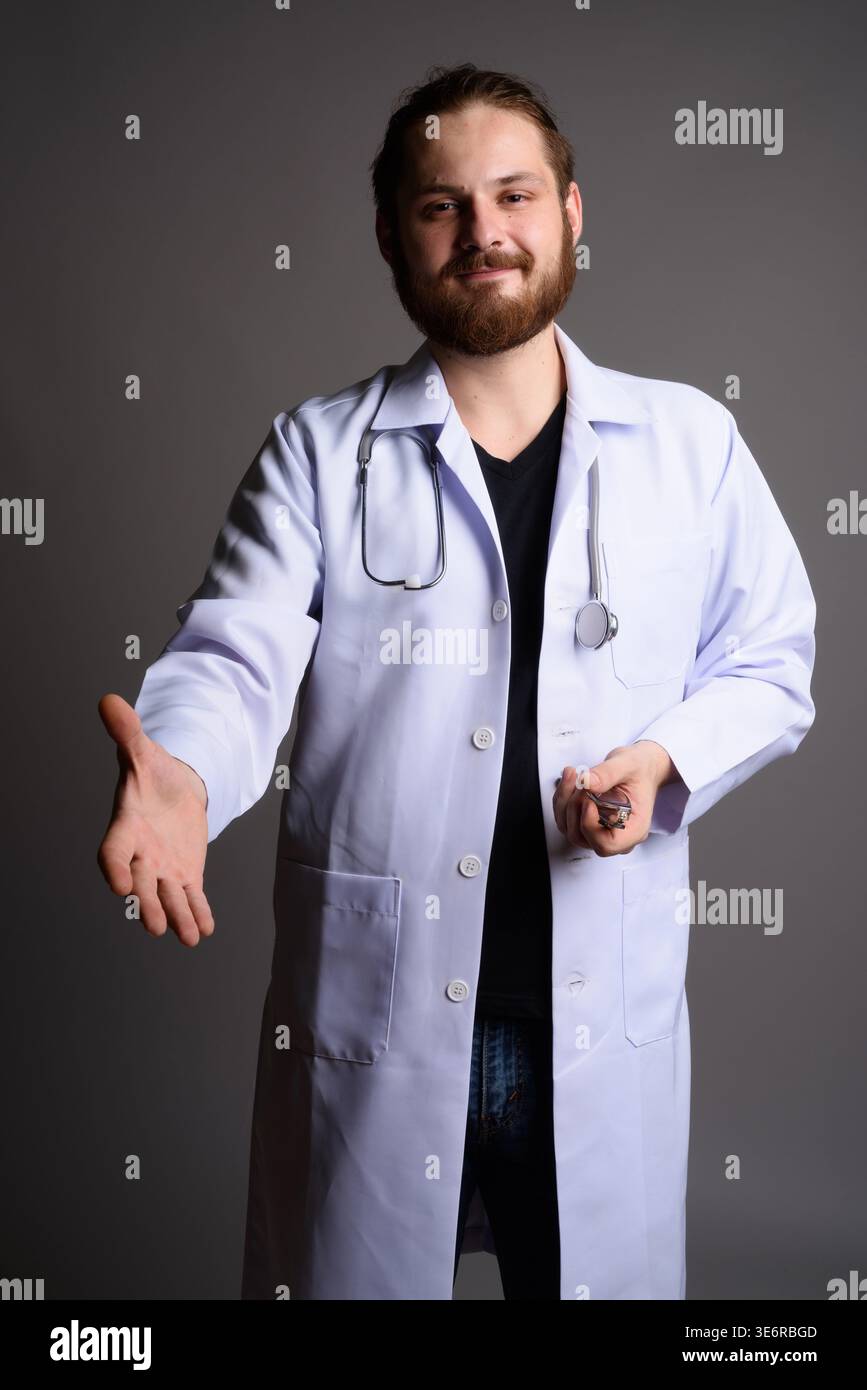 Studio portrait of a smiling bearded male doctor in a white lab coat ...
