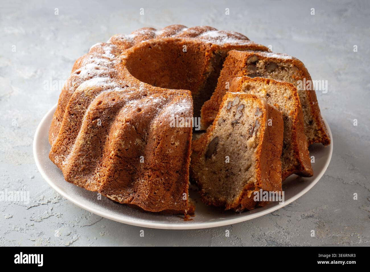 Homemade Sliced Bundt Cake with Walnuts and Cinnamon Sprinkled with Powdered Sugar Stock Photo