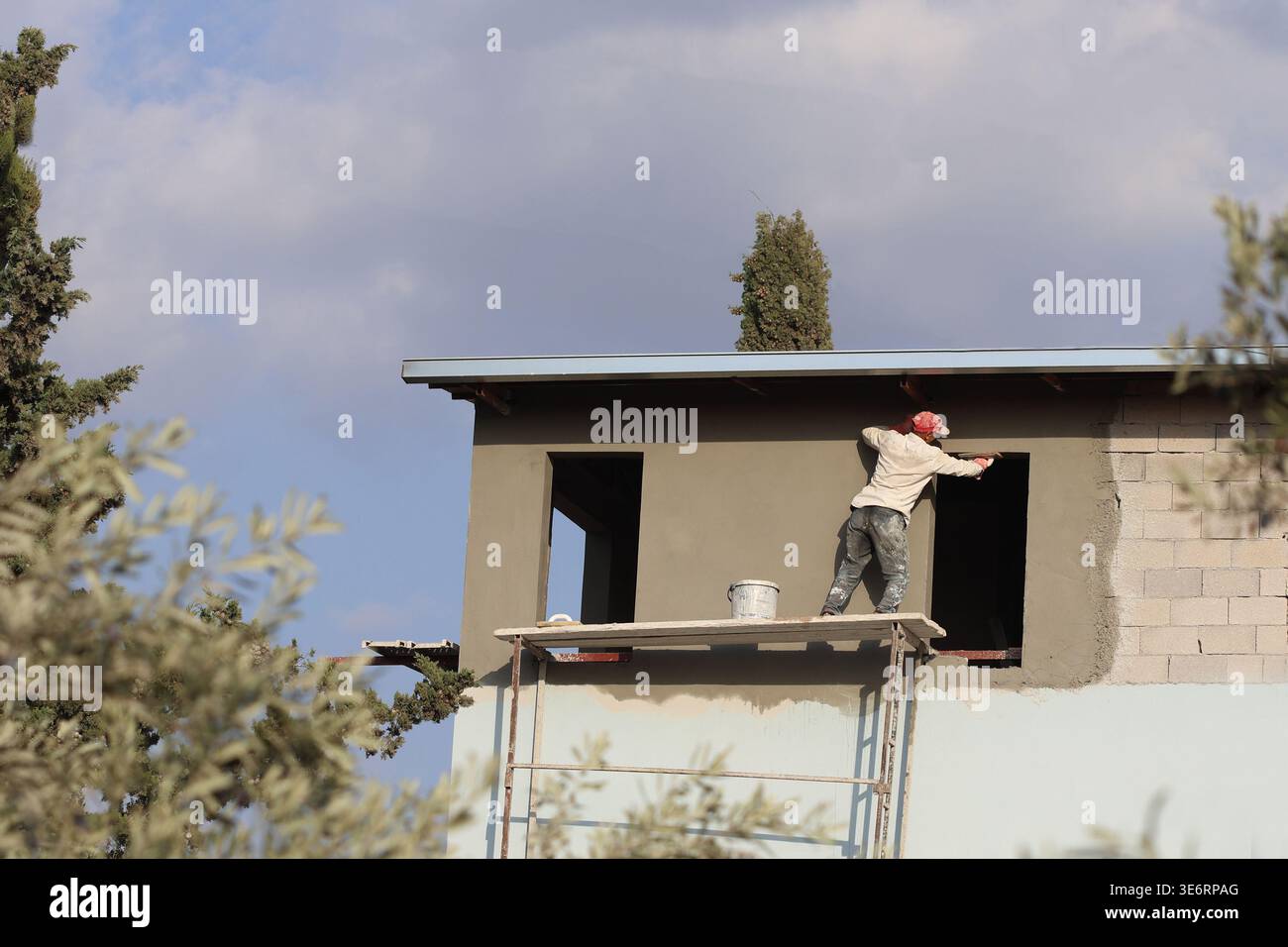 Plasterer working on a scaffold without any safety belt Stock Photo