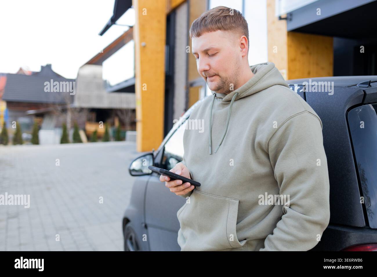 Man using smartphone standing near car outdoors Stock Photo