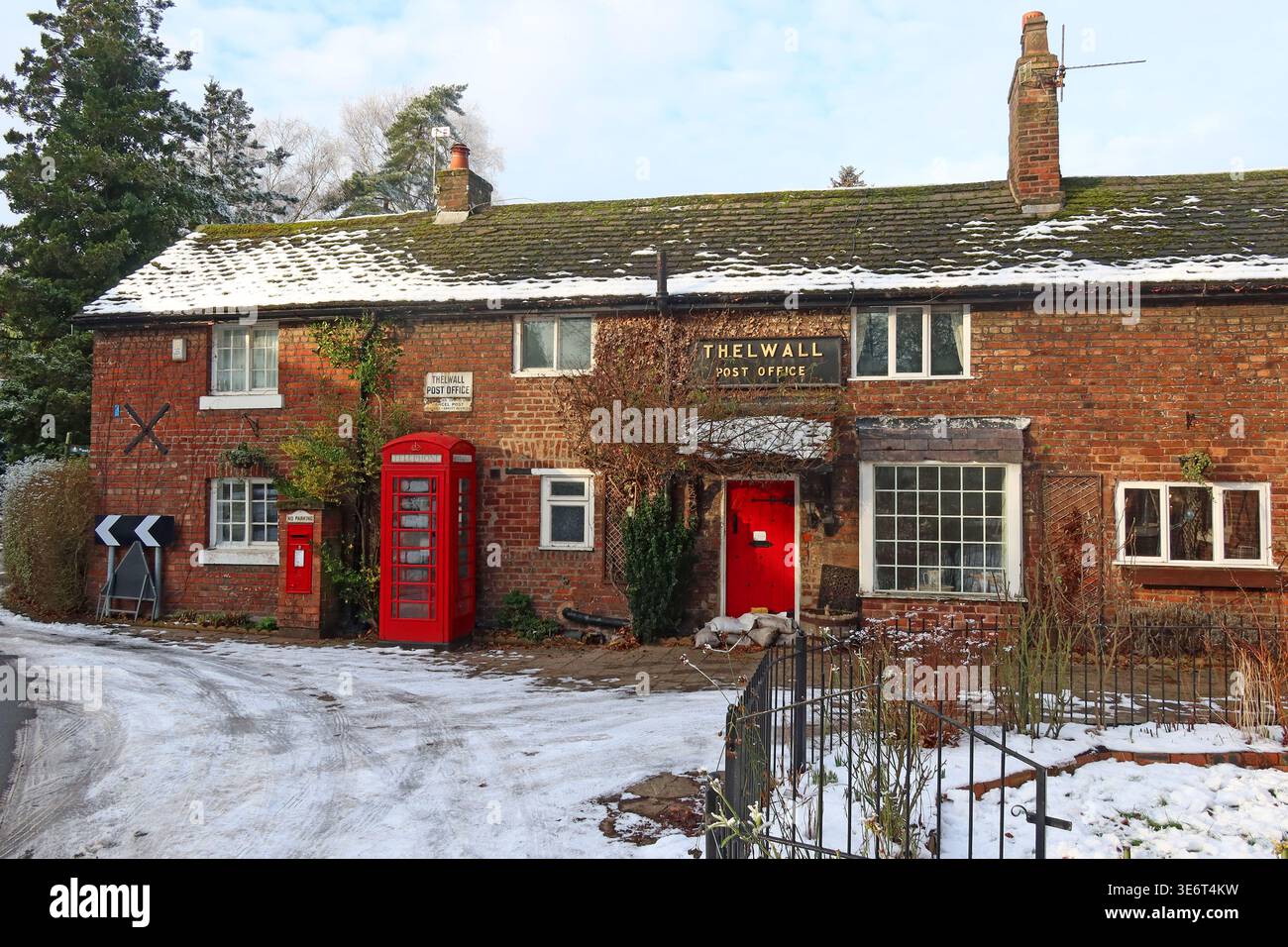 Former Thelwall Post Office building and red telephone box in snow, Warrington, Cheshire, England. Stock Photo