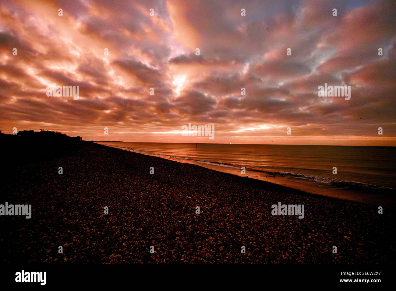 Dramatic stormy sunset over shingle beach and sea Stock Photo