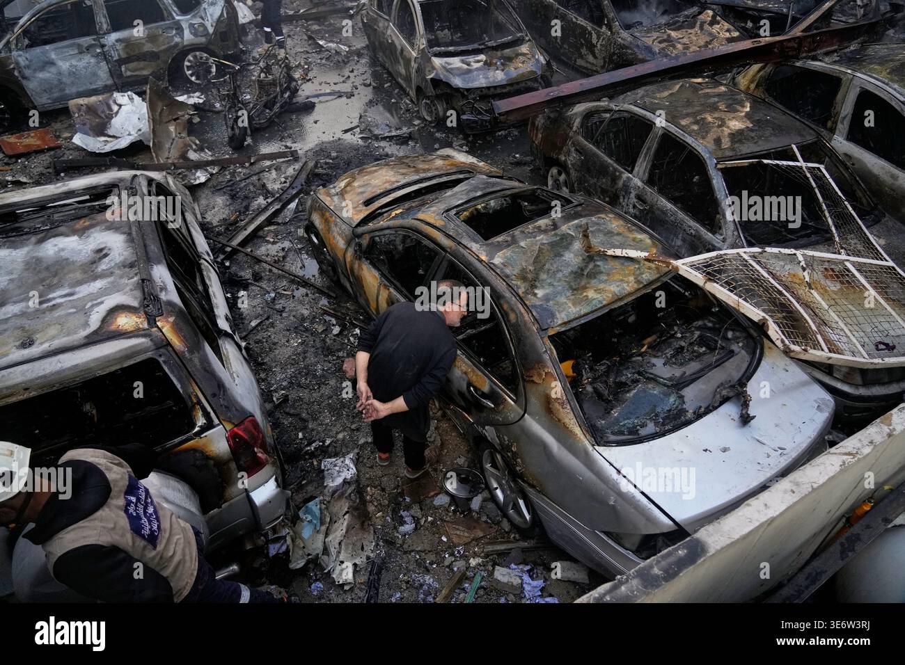A man peers inside a burned car at the site of an Israeli airstrike ...
