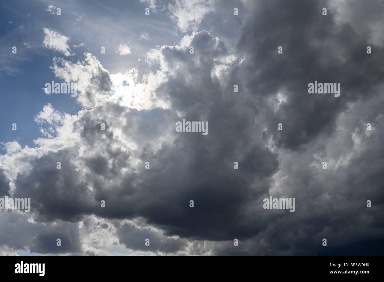 High-resolution photo of a stormy sky, featuring dense, dark clouds typical of stormy or rainy weather. The image highlights the dramatic contrast and Stock Photo