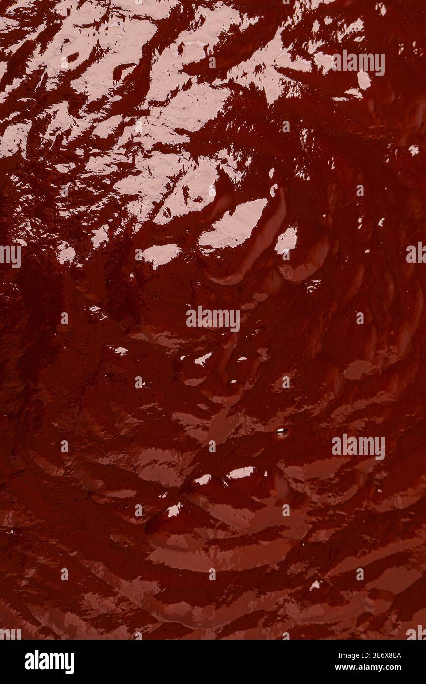 Dark red-brown liquid surface with glossy reflections creating an abstract texture Stock Photo