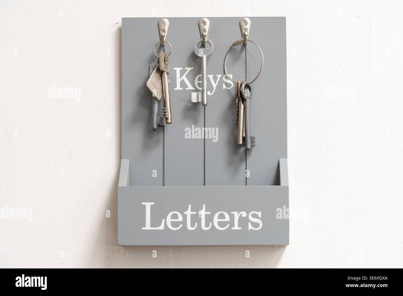 Keys hanging on hooks with gray labeled storage board Stock Photo