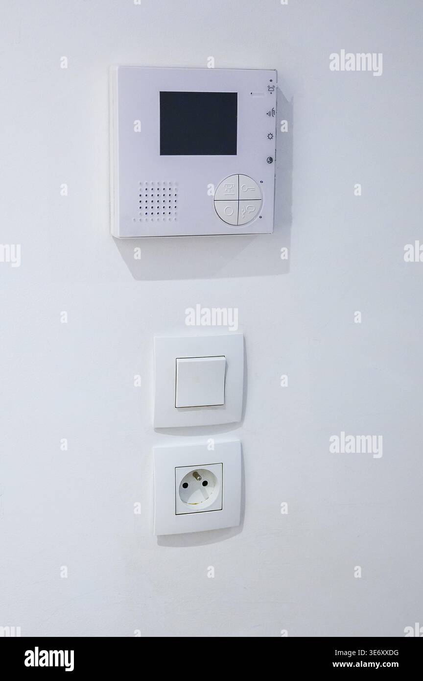 Modern white intercom system and electrical outlets mounted on a clean wall Stock Photo