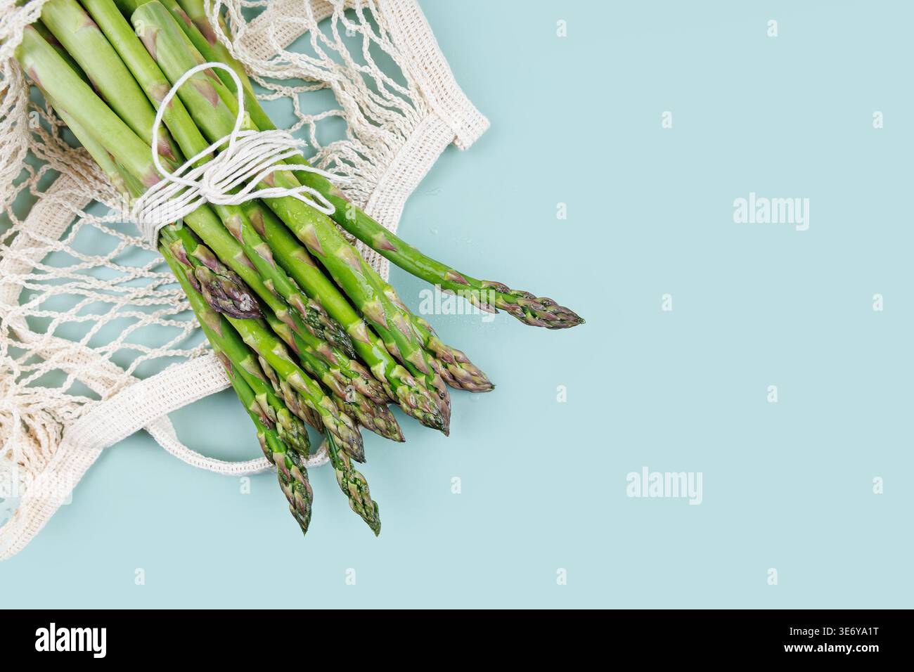 Flat lay of green asparagus in eco packaging with net bag on pastel ...