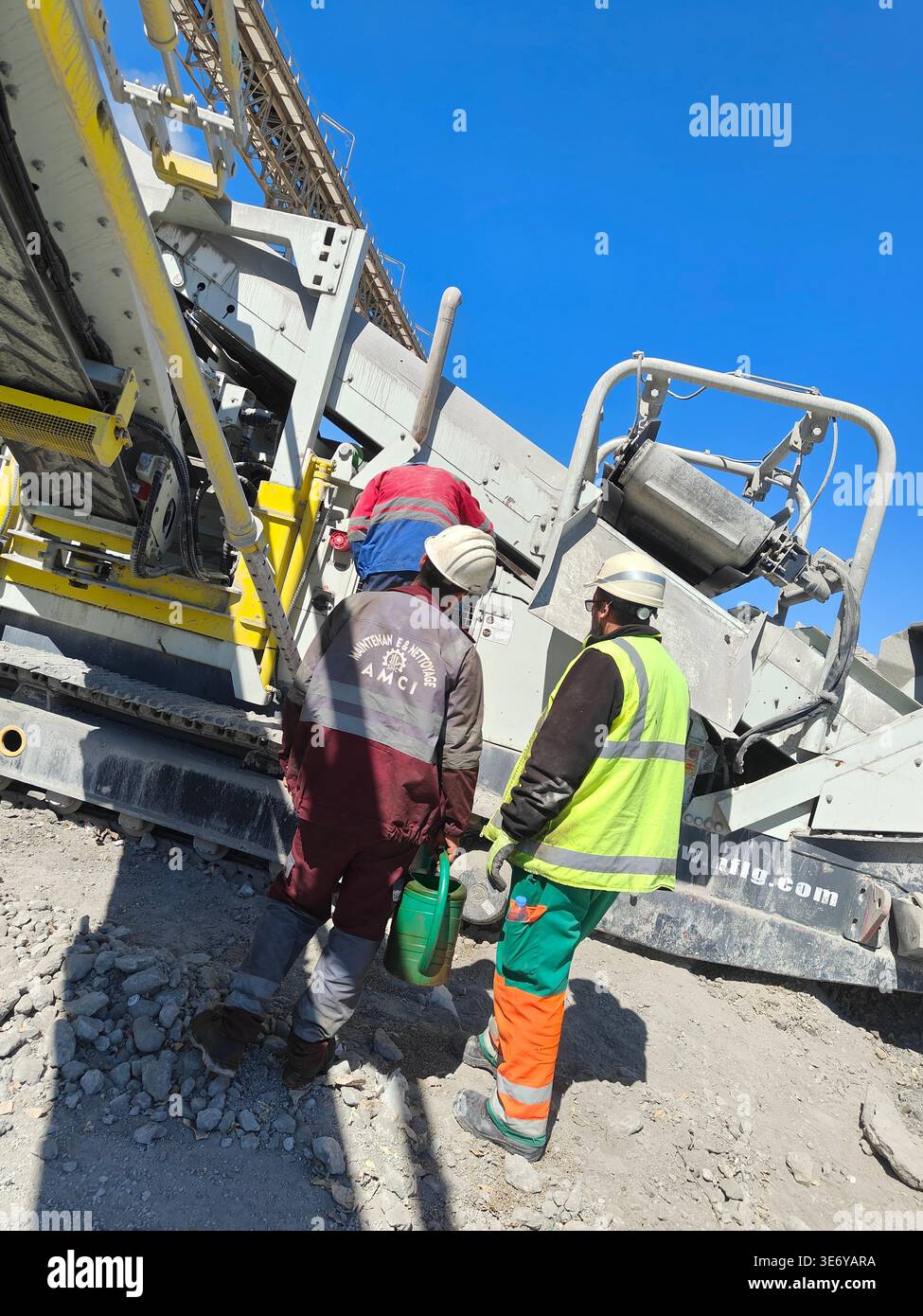 NFLG NFS 350 mobile screening plant processing cement, gravel, and aggregate in Algeria. Site workers inspecting machinery. - Smartphone Captured Stock Image