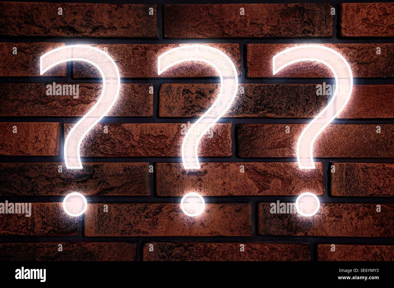 Three glowing question marks on brick wall Stock Photo
