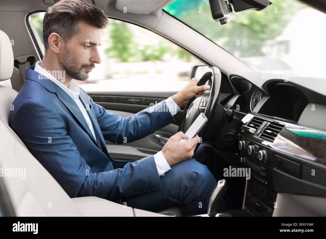 Businessman driving and texting on mobile phone Stock Photo