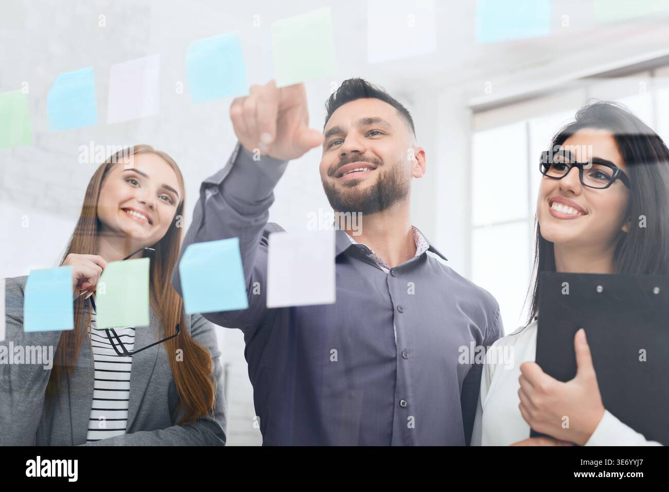 Businessman presenting ideas on sticky notes on glass wall Stock Photo