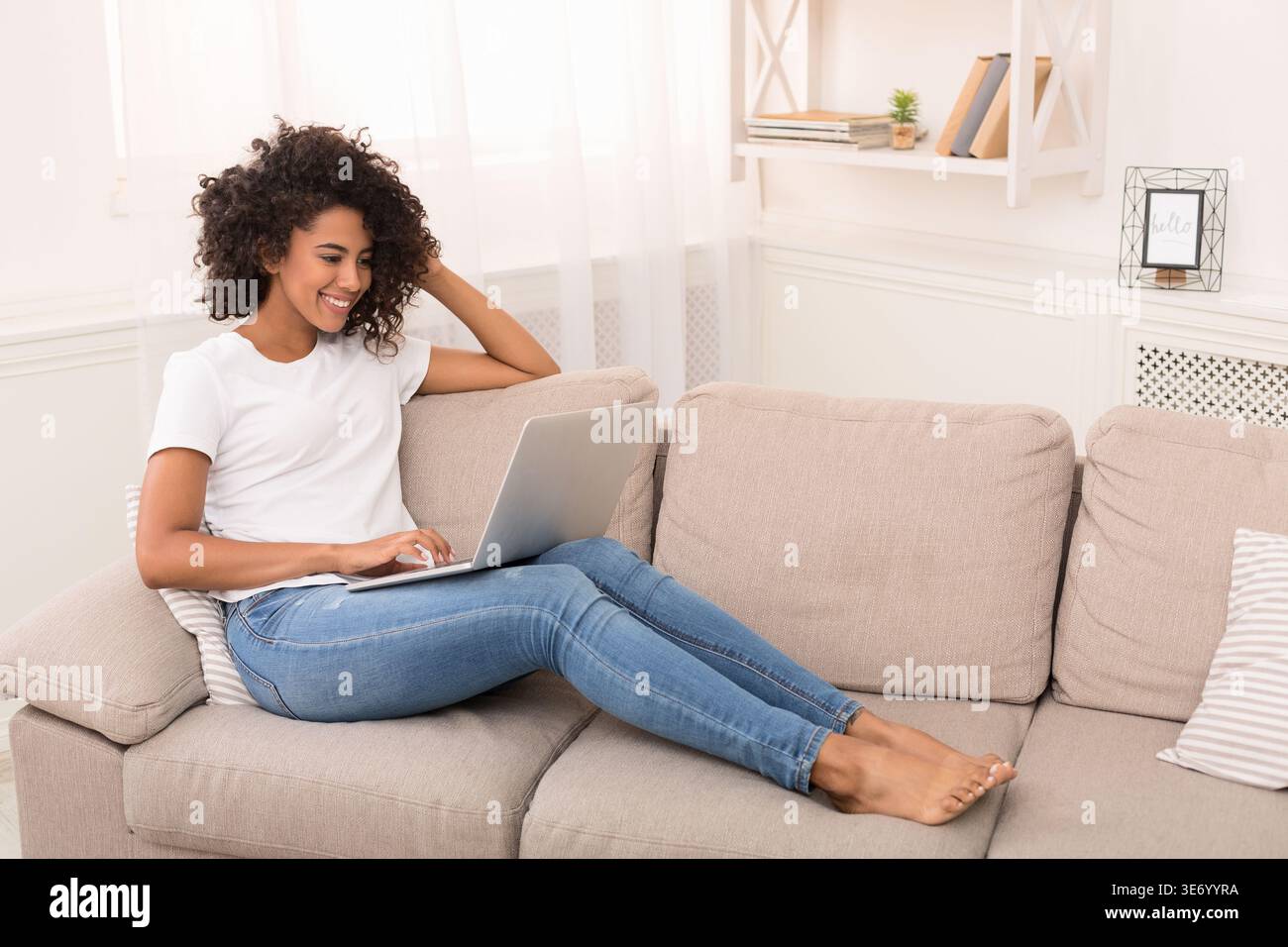 Attractive woman using laptop while relaxing on sofa Stock Photo