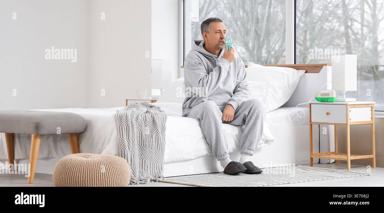 Mature man using nebulizer in bedroom Stock Photo