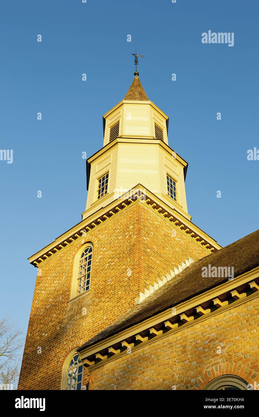 Warm sunlight at sunrise illuminates the brick tower of Bruton parish church in Williamsburg Stock Photo