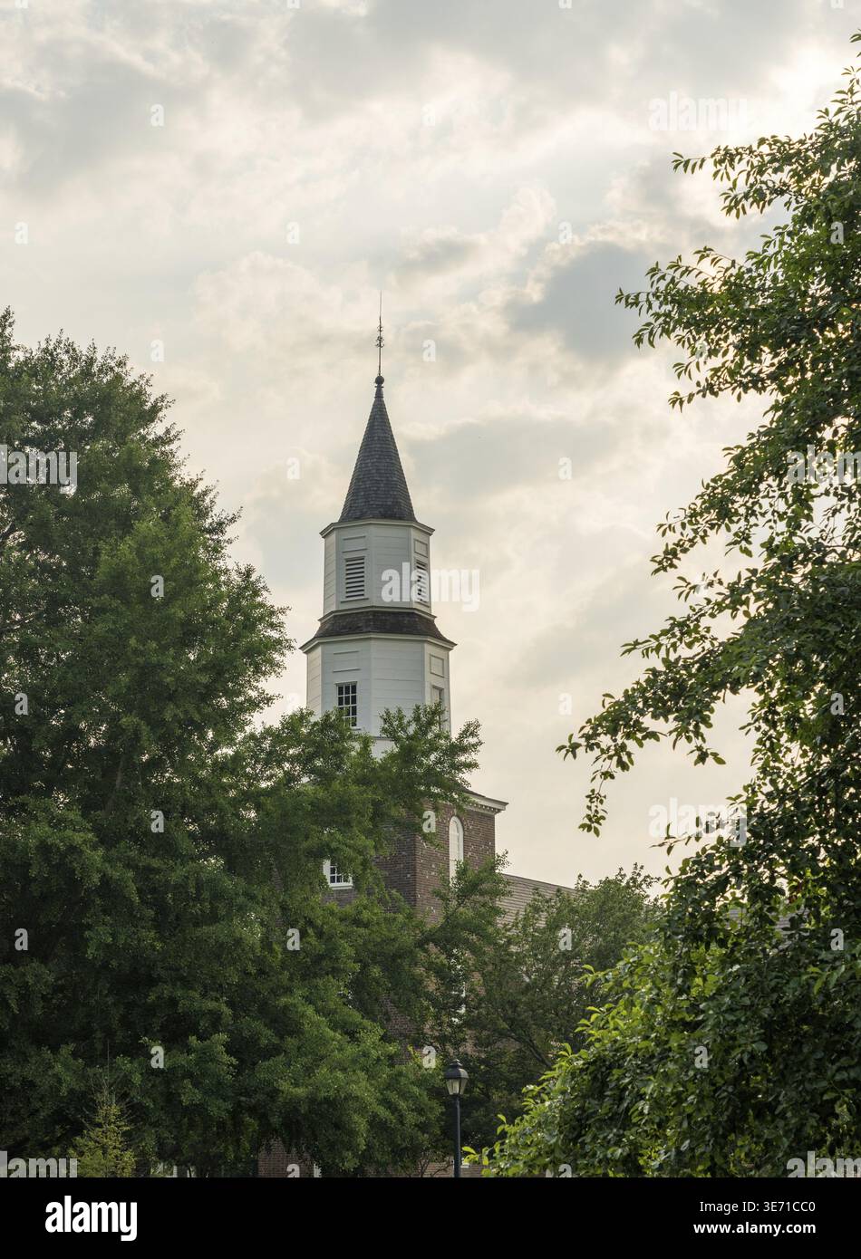 Warm sunlight at sunrise illuminates the brick and wooden tower of Bruton parish church in Williamsburg Stock Photo