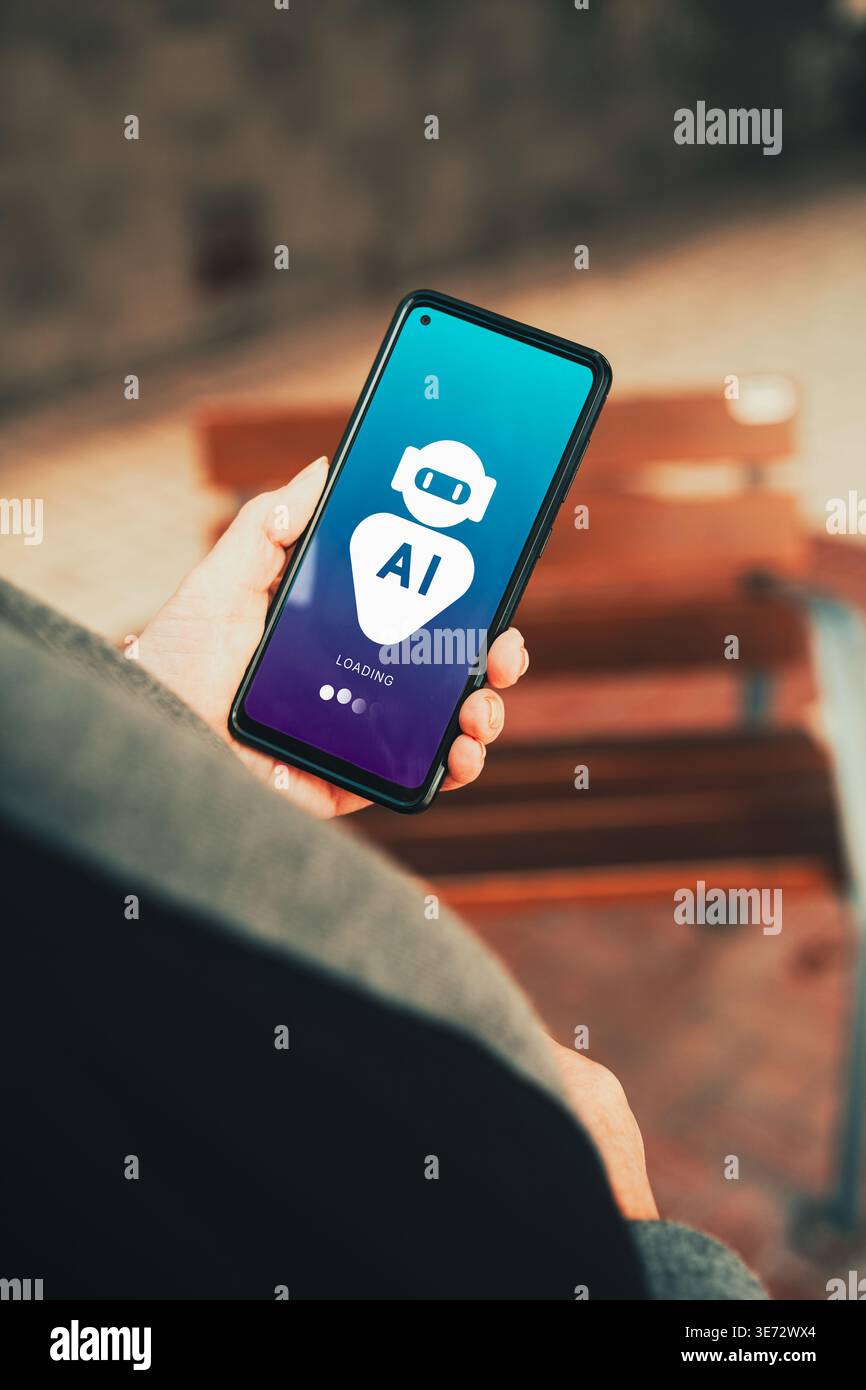 AI chatbot app loading on smartphone screen held by person outdoors. Digital transformation with Artificial Intelligence. Stock Photo