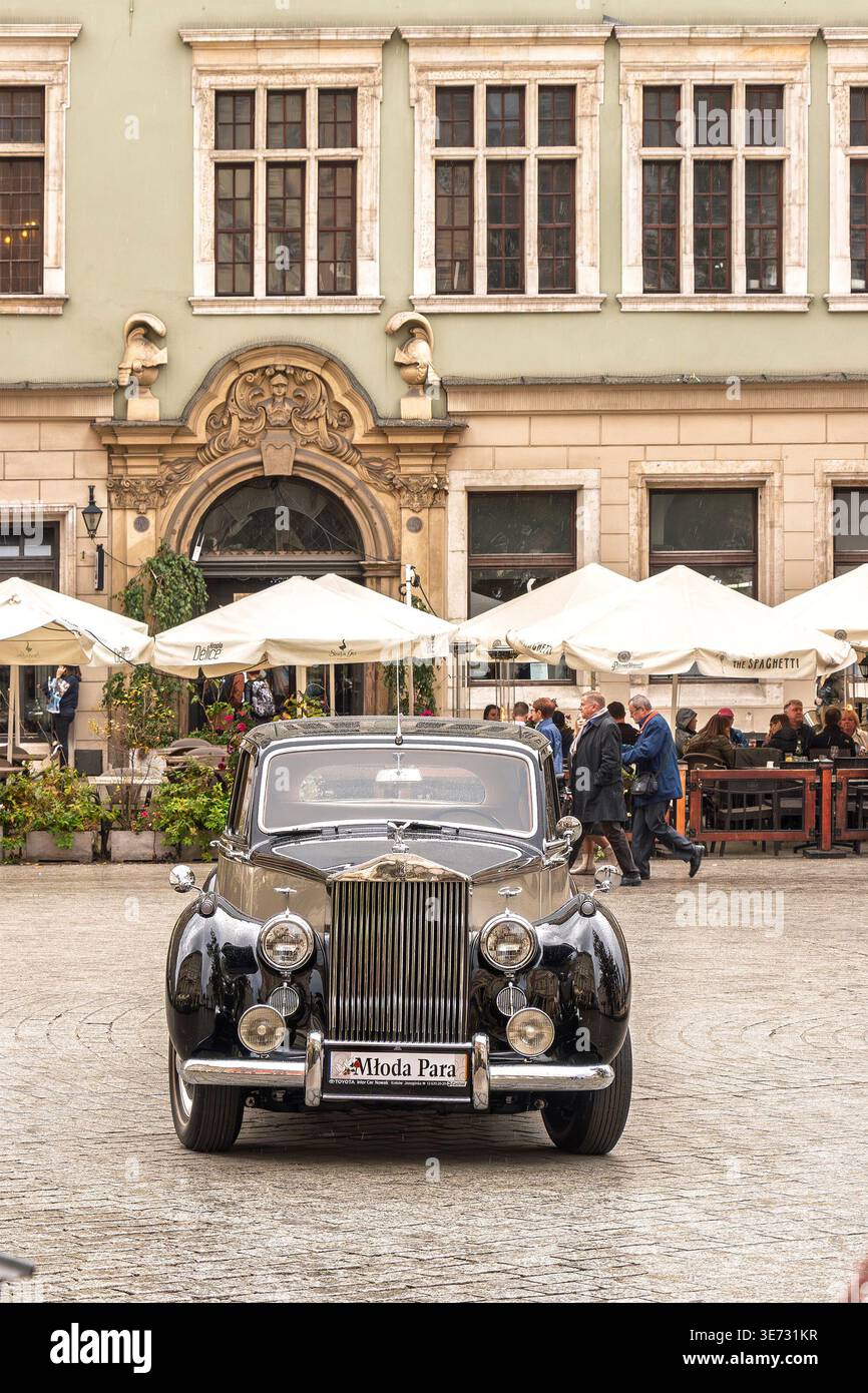 Classic black 1954 Rolls-Royce Silver Dawn vintage car parked on the cobblestone Main Market Square in Krakow Poland with historic architecture Stock Photo
