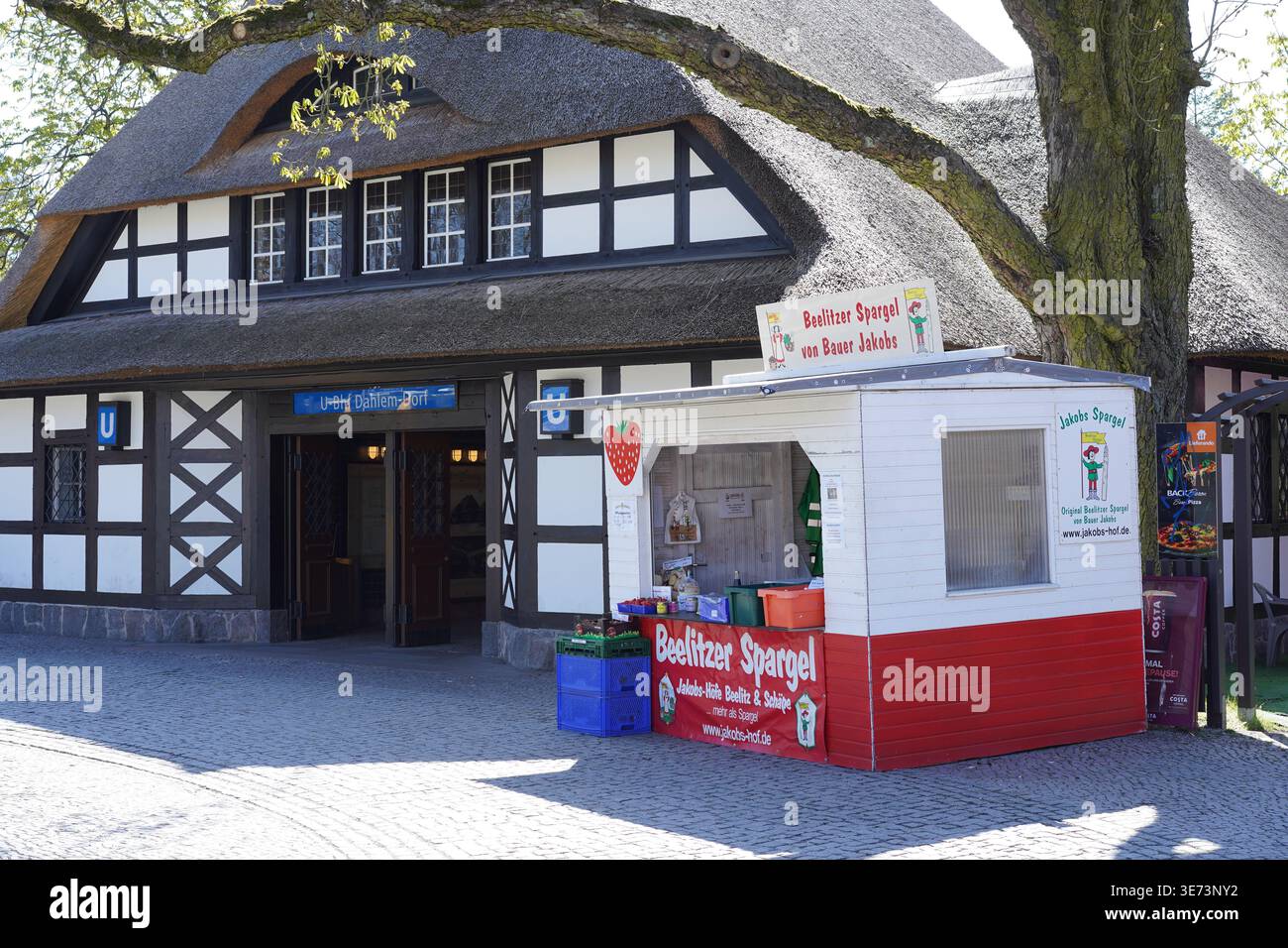 Berlin, Germany - April 9, 2026: A seasonal roadside stand selling Beelitz asparagus at the historic thatched roof subway station Dahlem-Dorf. Stock Photo