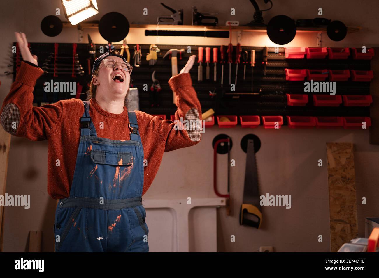 Angry female carpenter shouting with hands up in furious gesture in ...