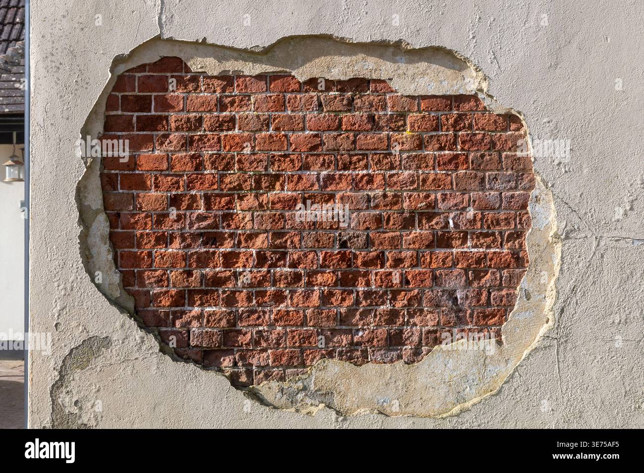 Hole in rendering or plasterwork exposing bricks brickwork on outside wall of house Stock Photo